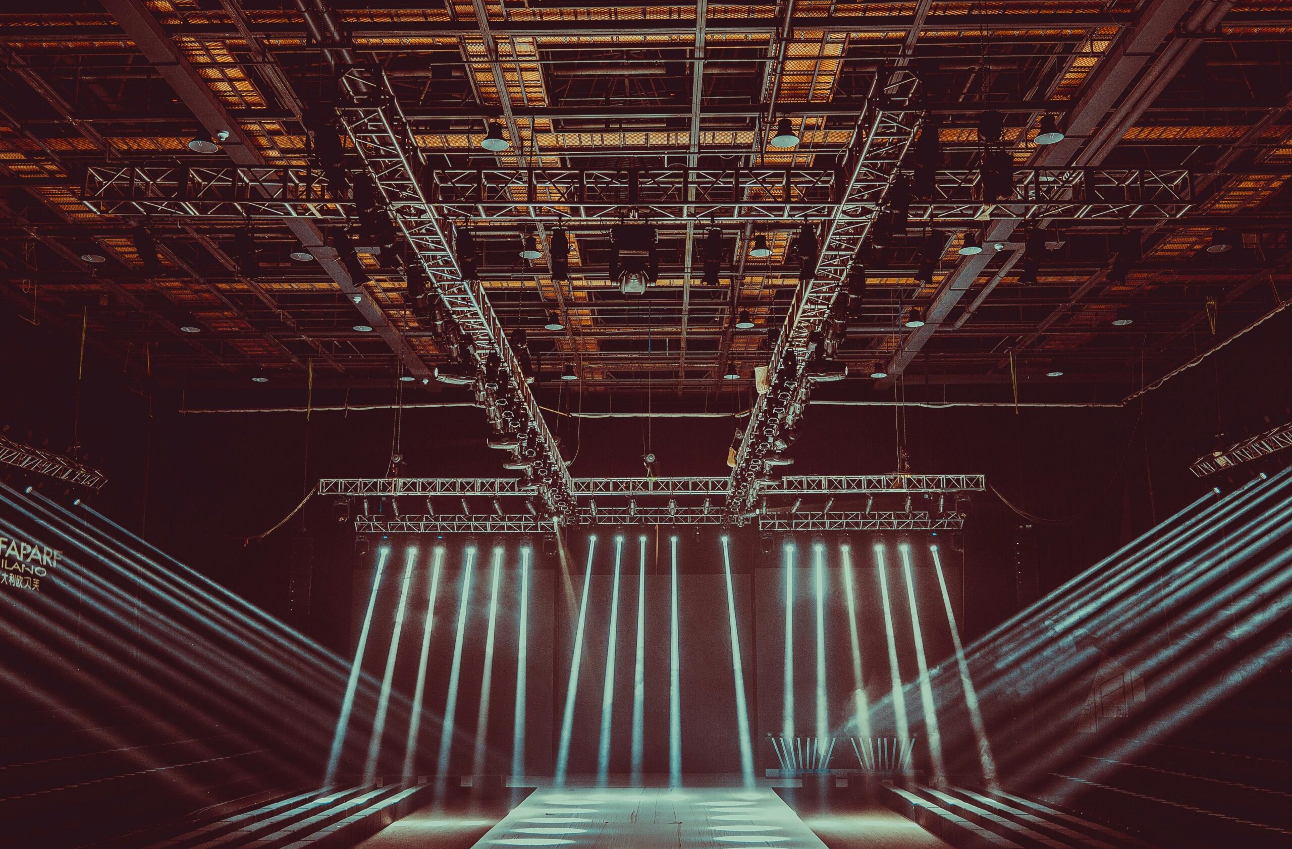 A contemporary indoor stage setup featuring dramatic lighting grid system and intricate architectural patterns.