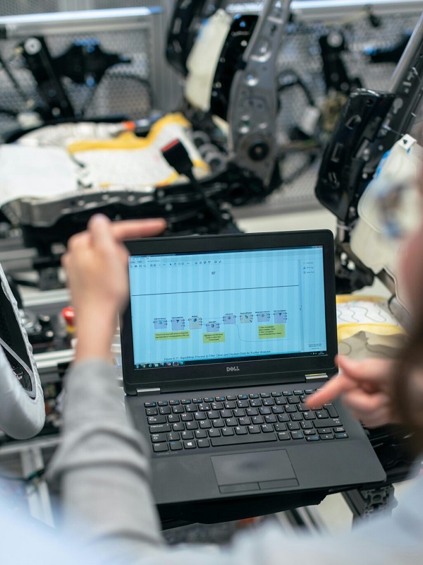 Engineers using a laptop to analyze software data in an industrial workshop setting.