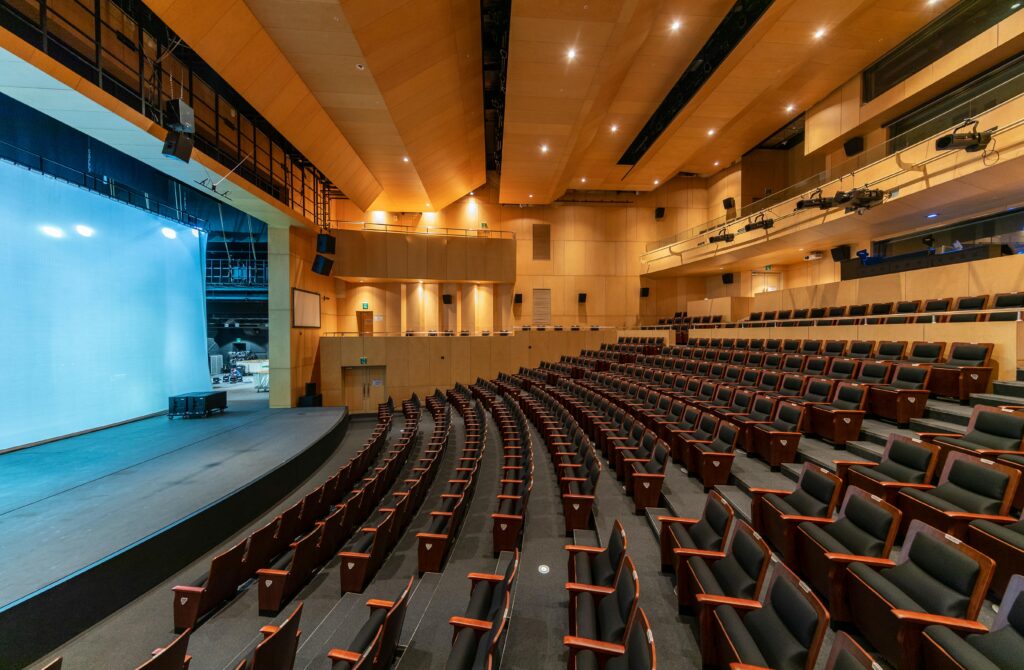 Spacious contemporary auditorium with empty seats and a stage, ideal for concerts or presentations.